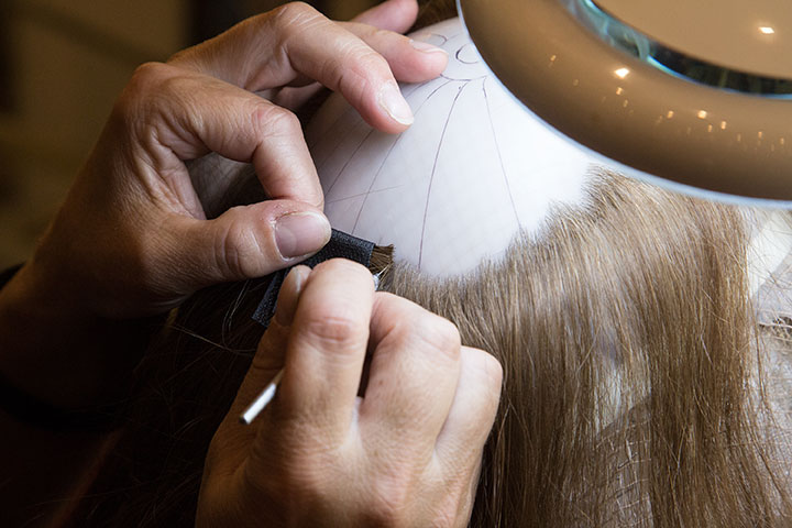 Hands working on a CRLAB custom hair prosthetic